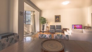A living room with a dining table, two sofas, a TV, and a potted plant. - LineRio Vista Mar Copacabana 228 (Rio de Janeiro)