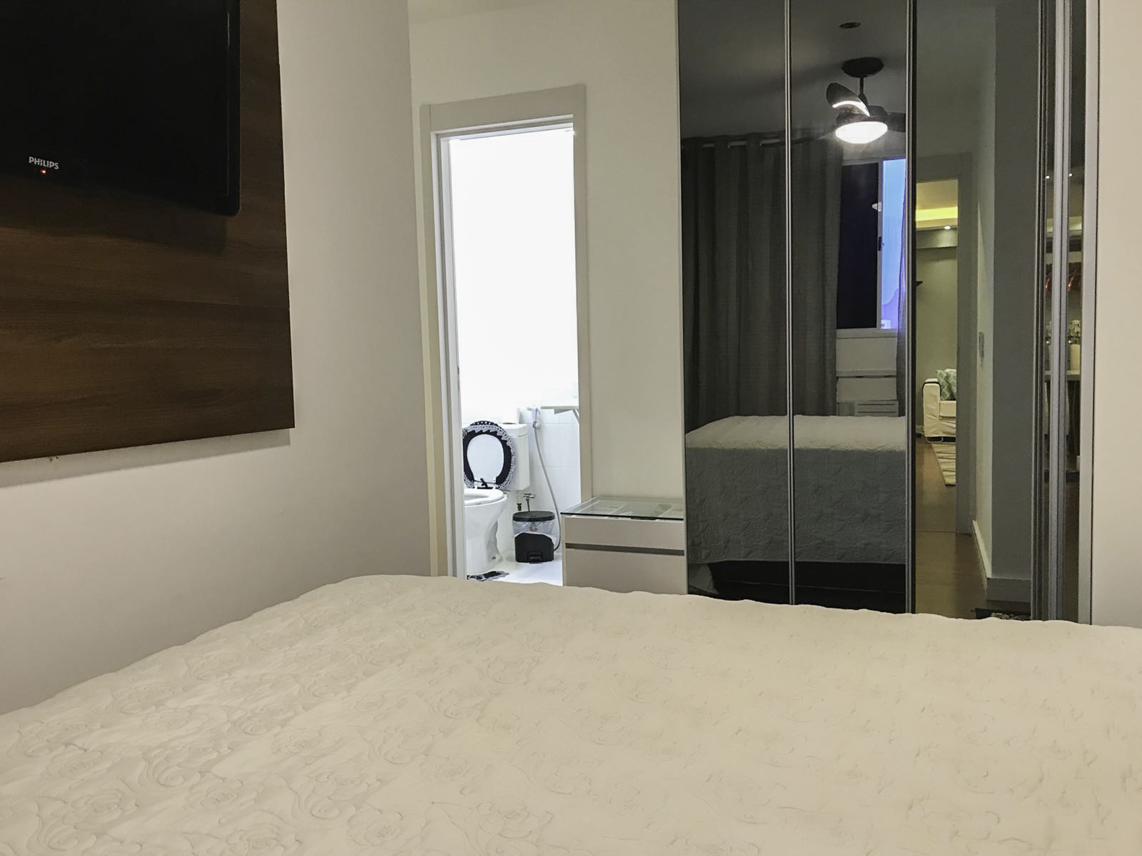 Una camera da letto con un letto, uno specchio, un WC e una cabina doccia.