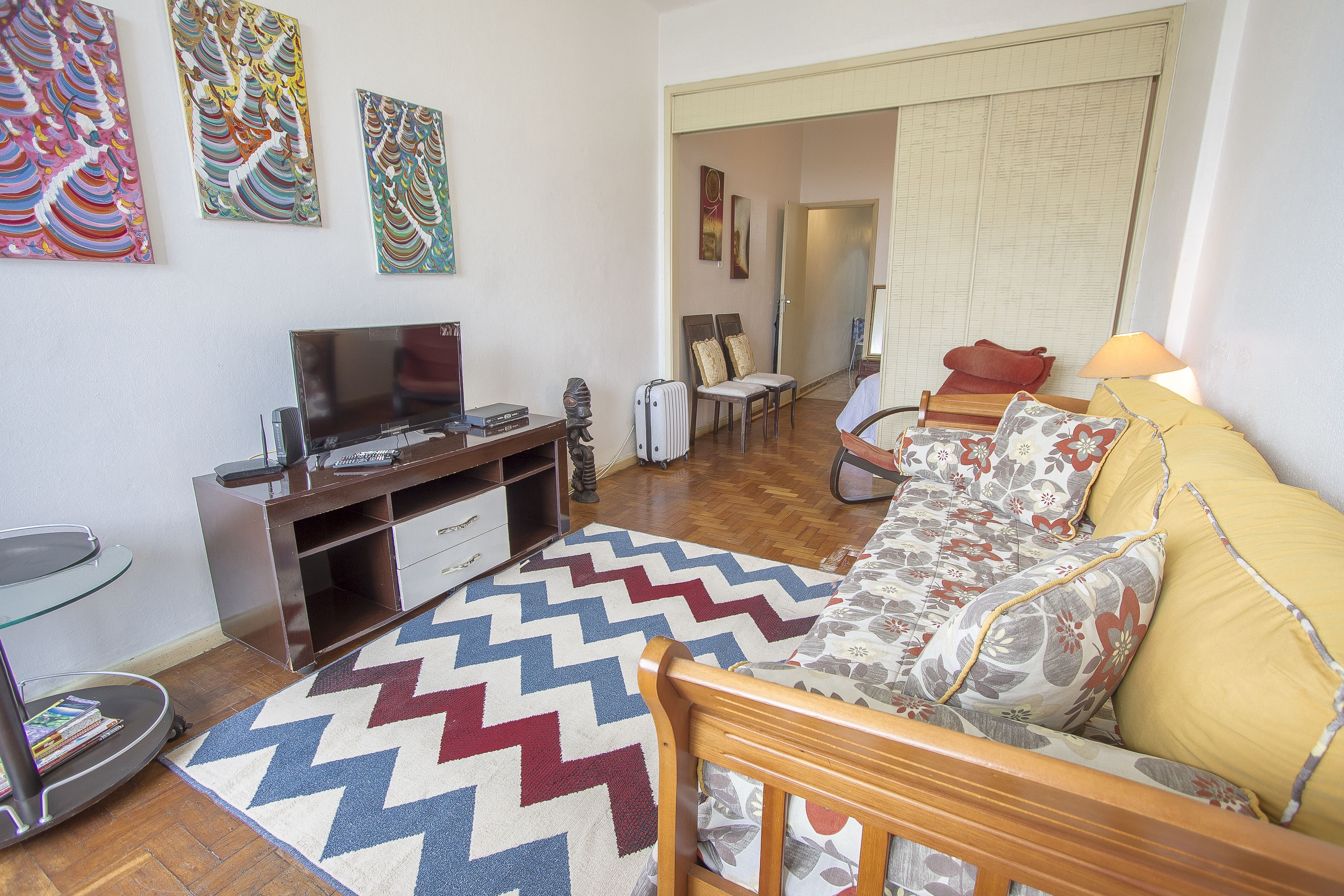 A living room with a sofa, a TV, a coffee table, and a patterned rug.