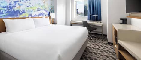 Una habitación de hotel con una cama grande, un escritorio, una silla y un televisor.