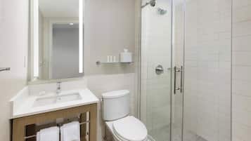 A modern bathroom with a glass-enclosed shower, a white sink, and a toilet.