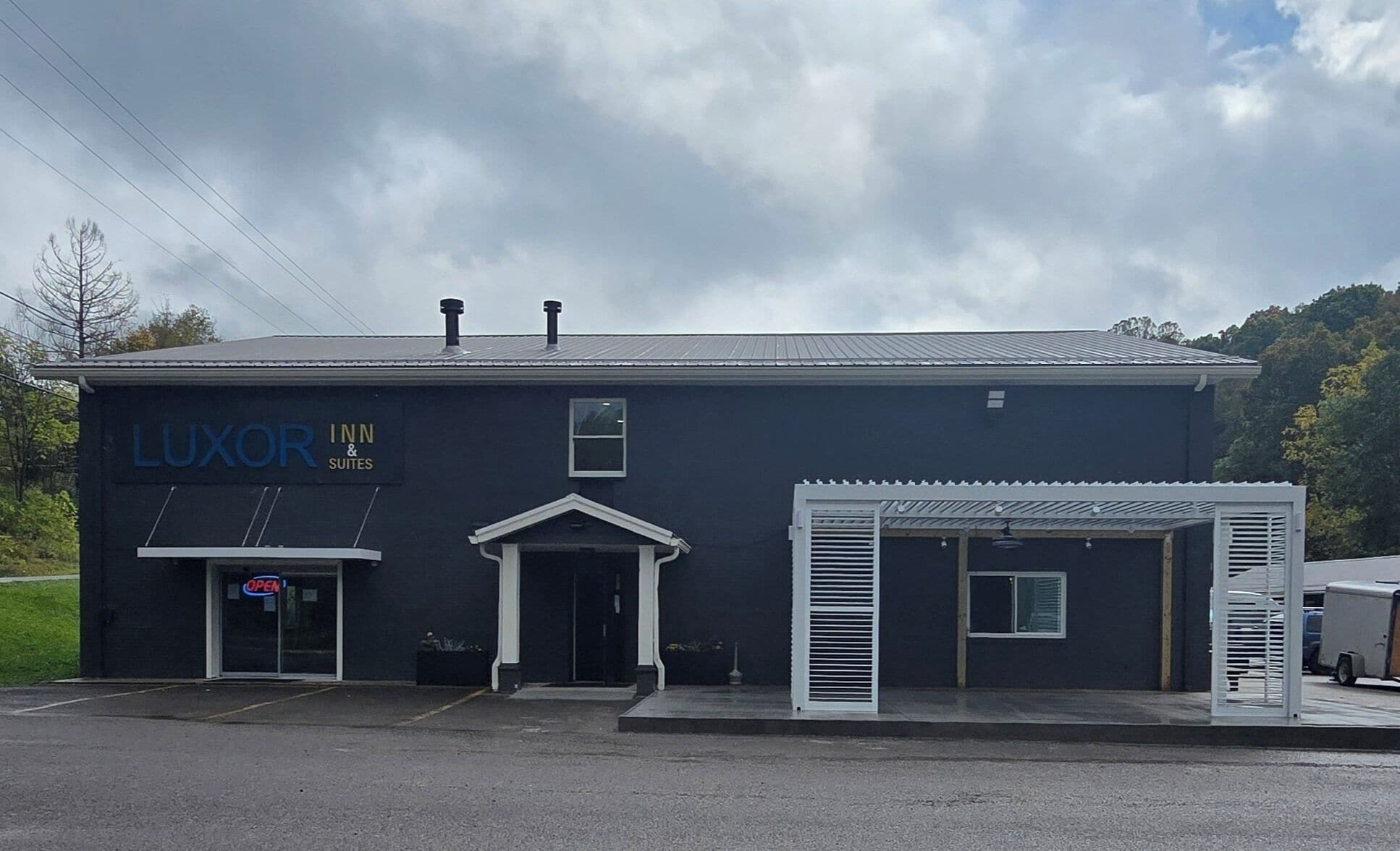A building with a sign reading "LUXOR INN & SUITES" and a "OPEN" sign on the door.