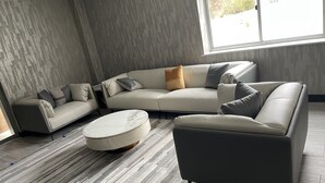 A modern living room with a sectional sofa, a round coffee table, and a dark armchair.