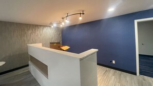 A reception area with a white counter, a patterned wall, and a blue accent wall.