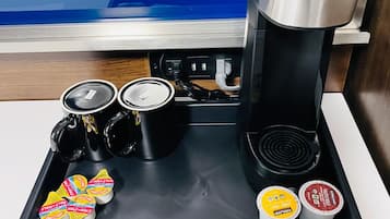 A coffee station with a coffee maker, milk frothing machine, and various milk and creamer containers.