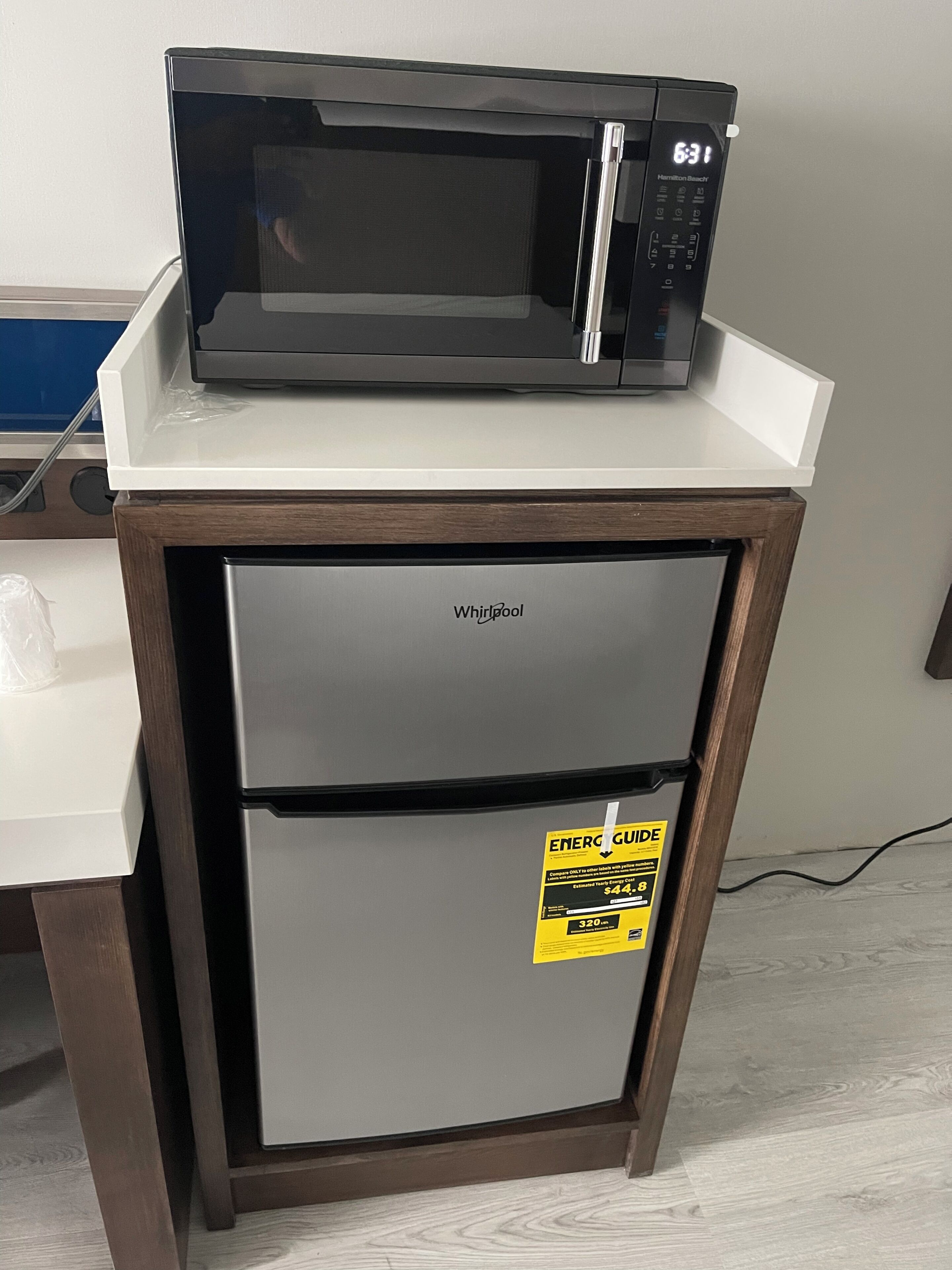 Een kleine keuken met een magnetron bovenop een Whirlpool koelkast.