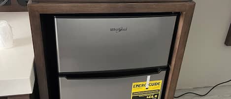 A compact kitchenette with a microwave on top of a Whirlpool refrigerator.