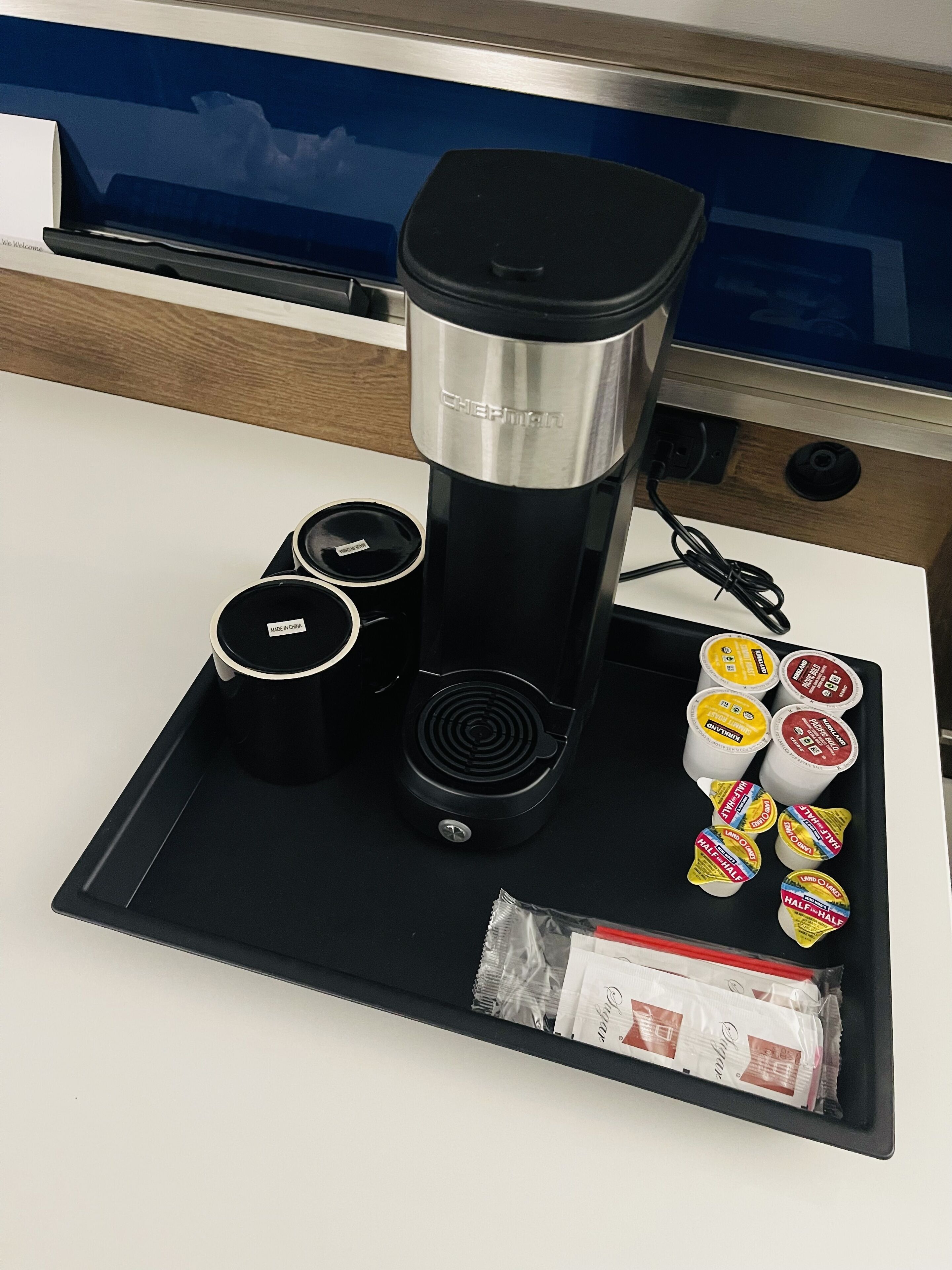 A coffee machine with a tray of coffee pods and a small packet of creamer.
