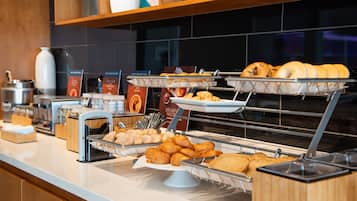 A breakfast buffet with various pastries and baked goods displayed on trays.