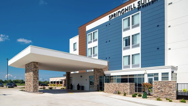 Un hôtel moderne, reconnaissable à son grand panneau « SPRINGHILL SUITES », doté d’une entrée couverte et d’un parking.