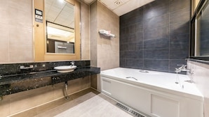 Ein modernes Badezimmer mit einem großen Spiegel, einer weißen Badewanne und einem schwarzen Waschtisch.