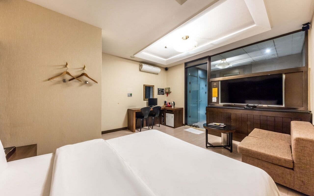Una habitación de hotel con cama, escritorio, silla, sofá y televisor.