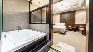 Ein modernes Badezimmer mit einer großen Badewanne und ein separates Schlafzimmer mit einem Bett und einem kleinen Tisch.