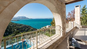 A balcony with a stone arch overlooking a pool and a sea view. - HECTORAS VILLA in Plaka-BY APOKORONAS VILLAS (Πλάκα)
