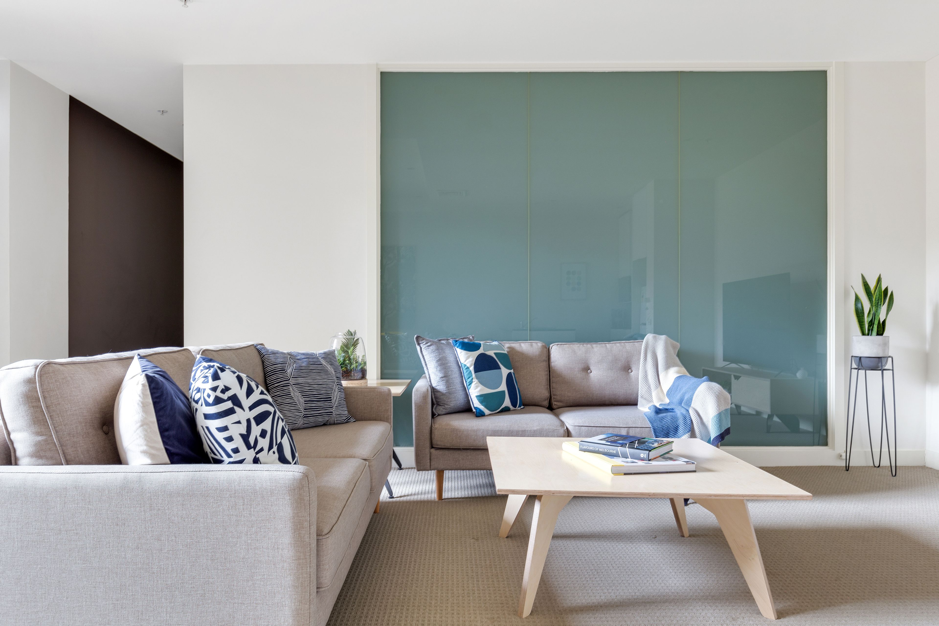 A modern living room with a sofa, a coffee table, and a large window.