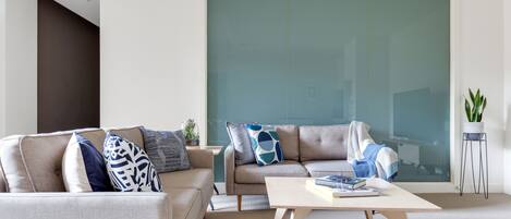 A modern living room with a sofa, a coffee table, and a large window.