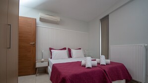A bedroom with a bed, white bedding, a nightstand, a lamp, and a radiator. - Prime 3BR/2BA Apt Heart of Heraklion-Fiber WIFI–Steps to Lions Sq Walk to Port 2 (Ηράκλειο)