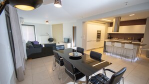 A modern living room with a dining area, a kitchen, and a seating area with a sofa and a TV. - Prime 3BR/2BA Apt Heart of Heraklion-Fiber WIFI–Steps to Lions Sq Walk to Port 2 (Ηράκλειο)