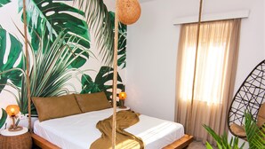 A bedroom with a bed, a hanging chair, and a large plant. - Villa Sea View (Ρέθυμνο)