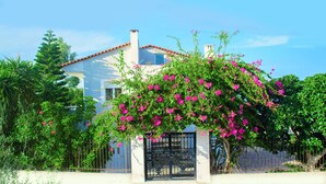 A house with a white exterior, a red-tiled roof, and a black gate. - Villa Sea View (Ρέθυμνο)