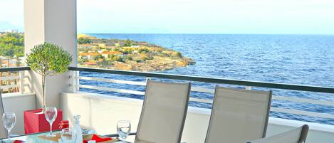 Une table dressée pour deux personnes, avec vue sur la mer et une île au loin.