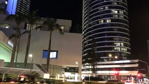 A modern hotel with a curved facade, multiple floors, and illuminated windows. - Large Apartment at Oracle Resort (Broadbeach)