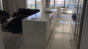 A modern apartment with a living area, kitchenette, and a balcony with a city view. - Large Apartment at Oracle Resort (Broadbeach)