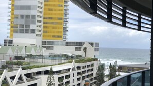 A modern building with multiple floors, a prominent yellow section, and a view of the ocean. - Large Apartment at Oracle Resort (Broadbeach)