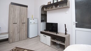 Pieni, käytännöllinen keittiö, jossa on jääkaappi, televisio ja puinen kaappi.