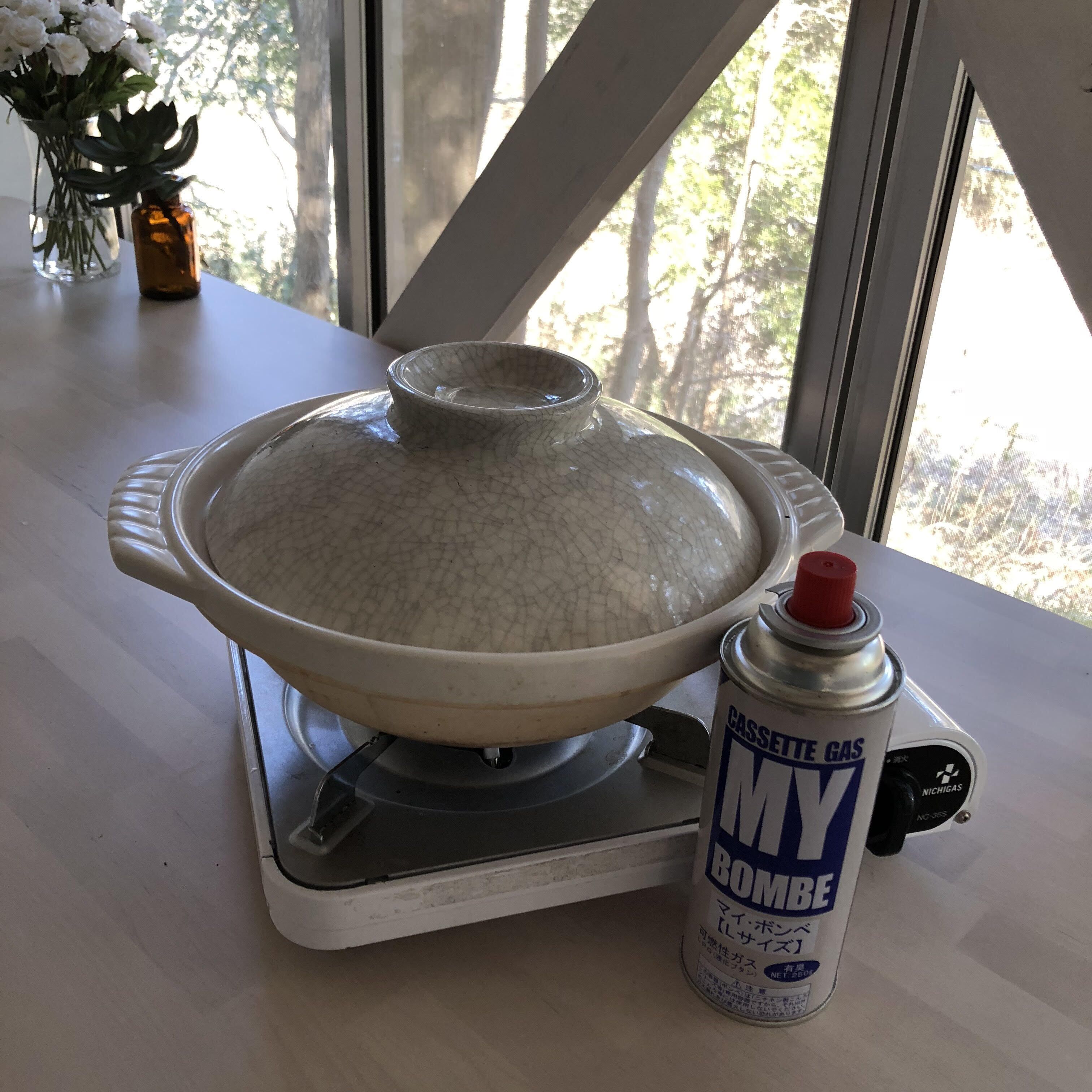 A kitchen with a stove, a pot, and a can of My Bombe gas canister.
