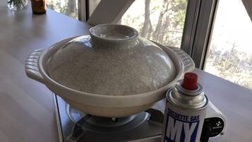 A kitchen with a stove, a pot, and a can of My Bombe gas canister.