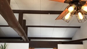 Une pièce avec des poutres apparentes, un ventilateur de plafond et un cadre de porte en bois renforcé par des traverses.