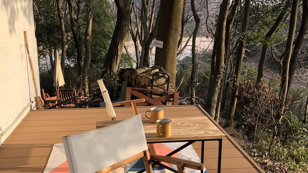 Une terrasse en bois avec une chaise et une table, entourée d’arbres.