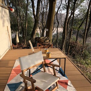 Eine Holzterrasse mit Stuhl und Tisch, umgeben von Bäumen.
