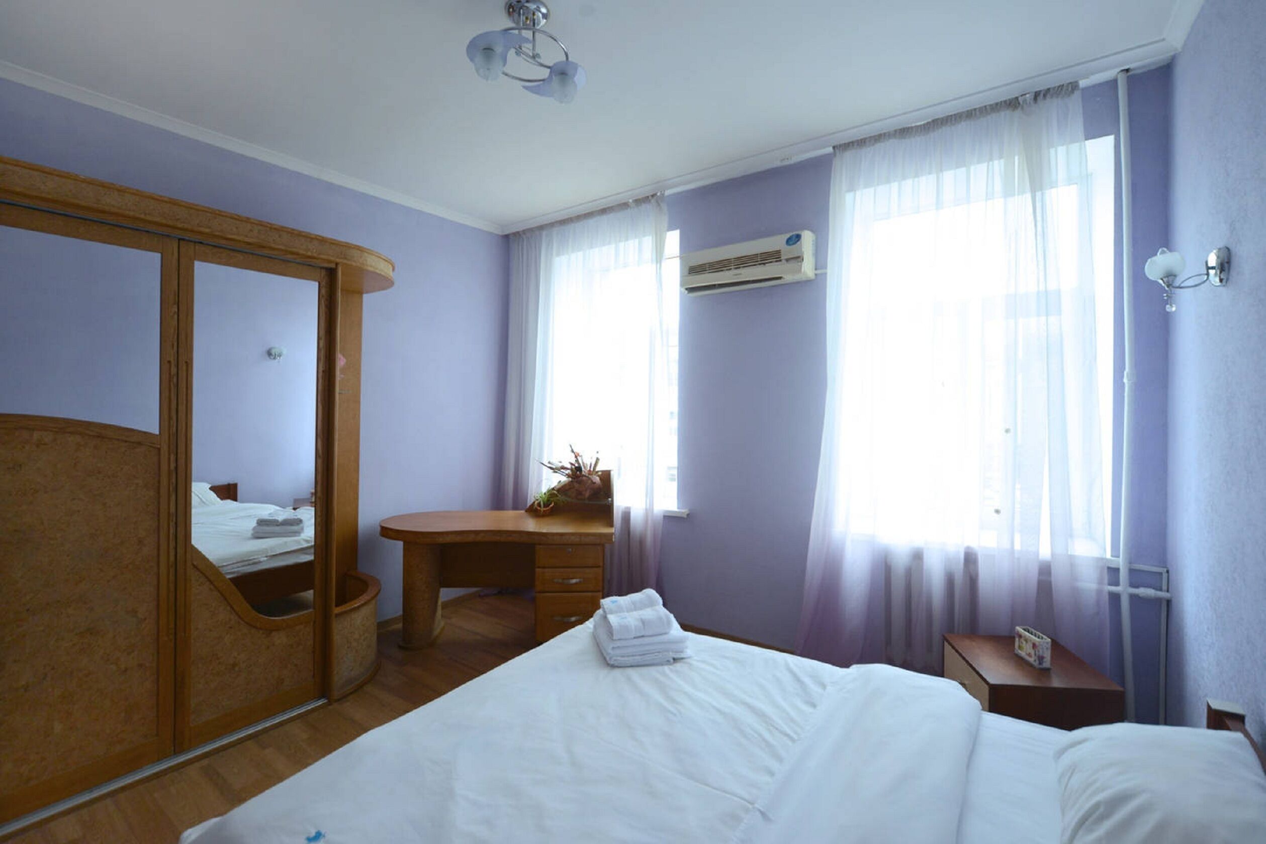 Une chambre d’hôtel comprenant un lit, une armoire en bois, un bureau et un appareil de climatisation.