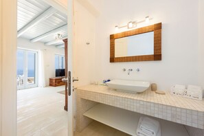 A bathroom with a white sink, a mirror with a wooden frame, and a tiled floor.