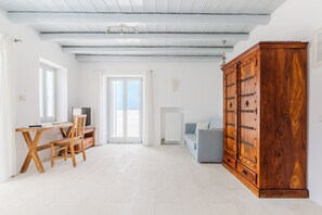 A spacious room with a wooden desk, a chair, a television, a large wardrobe, and a sofa.
