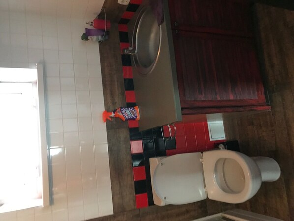 A modern bathroom with a toilet, bidet, and hand soap, set against a backdrop of a patterned floor.