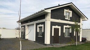 A two-story house with a black and white exterior, a garage door, and a small lawn. - Guest House near Kiev  (Софиевская Борщаговка)