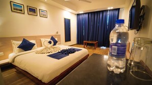 A hotel room with a bed, a water bottle, and a glass of water on a table. - The Euphoria Grand (Shimla)