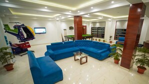 A modern lobby with a blue sectional sofa, a pool table, and a mounted helicopter. - The Euphoria Grand (Shimla)