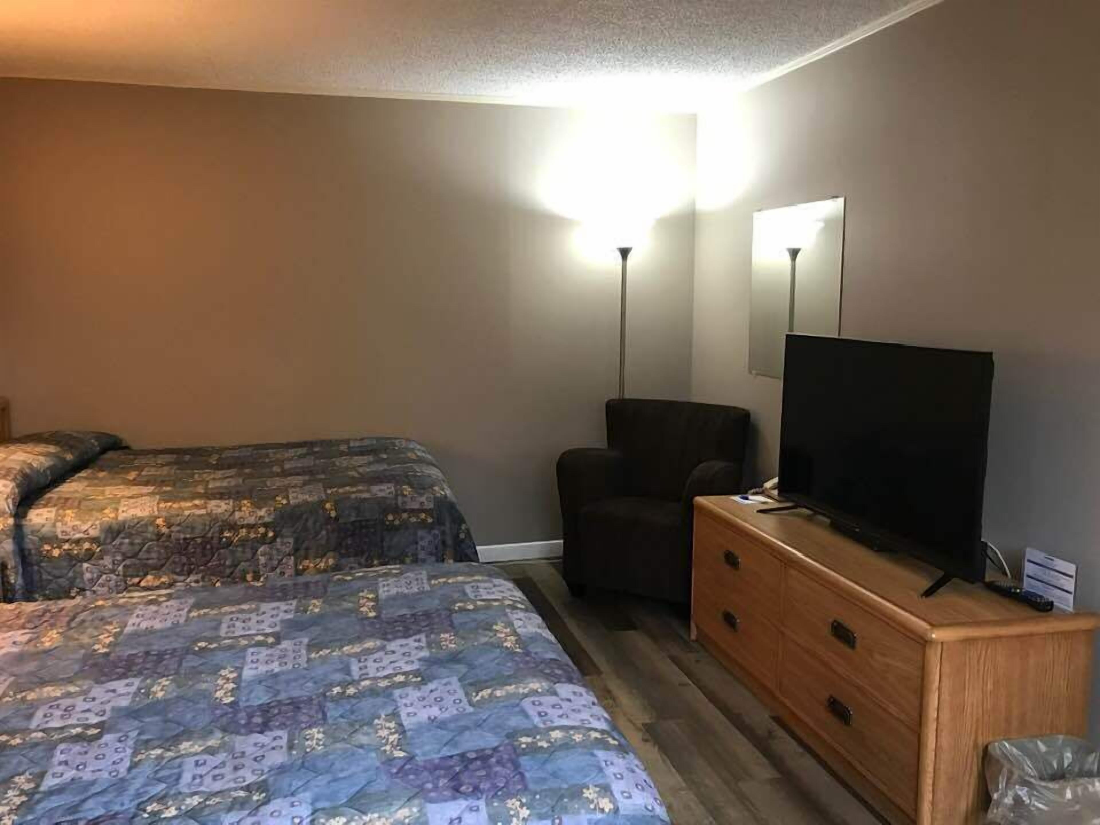 A hotel room with two beds, a desk with a television, and a chair.