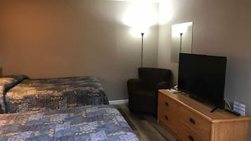 Et hotelværelse med to senge, et skrivebord med tv og en lænestol.