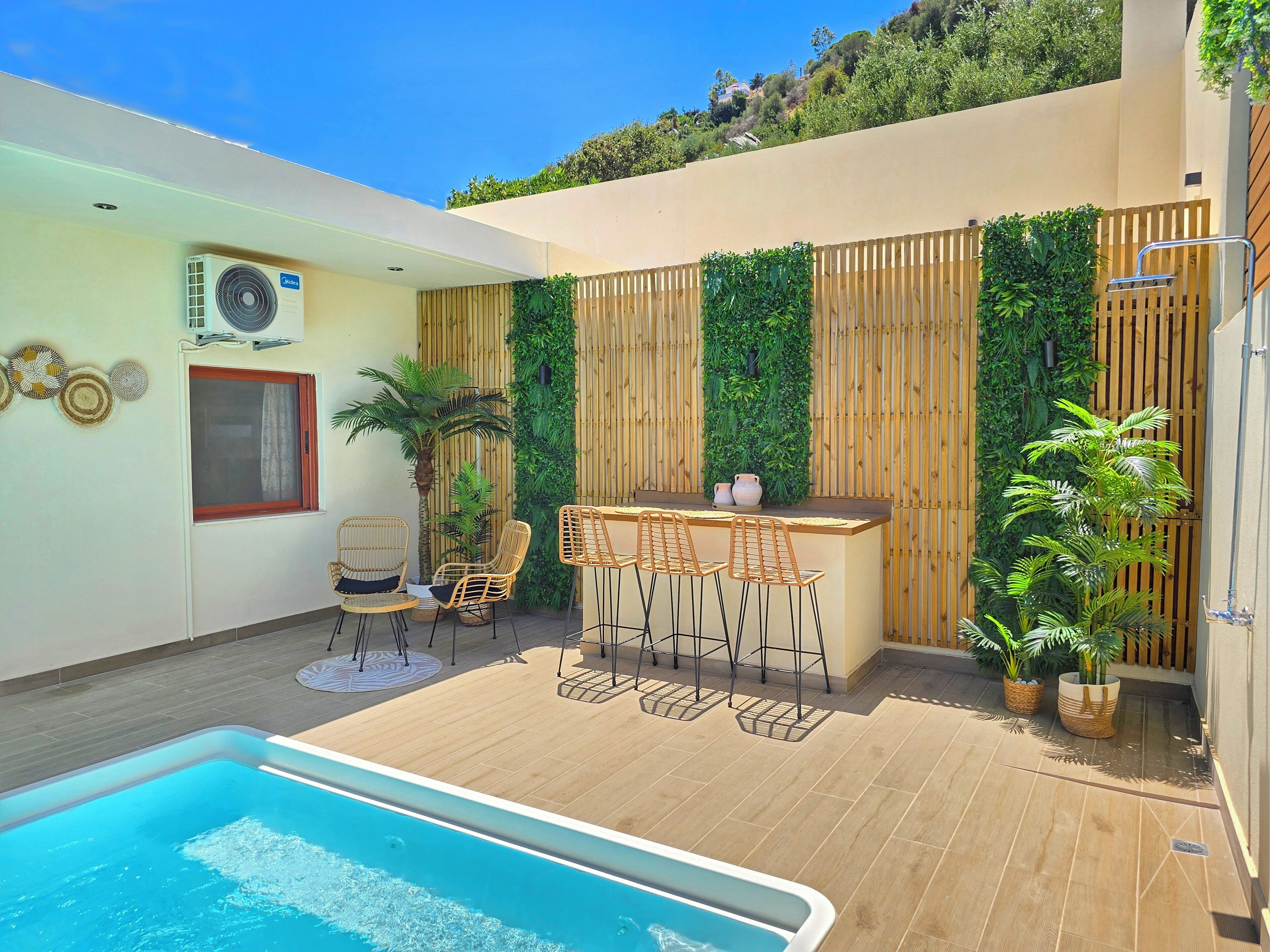 A poolside area with a bar, seating, and a view of a hillside.