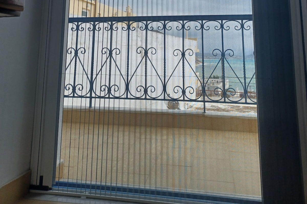 A balcony with a metal railing and a view of the sky and buildings.