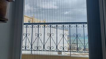 Een balkon met een metalen hekwerk en uitzicht op de lucht en gebouwen.