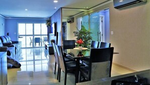 A modern living room with a glass dining table, black chairs, and a sofa.