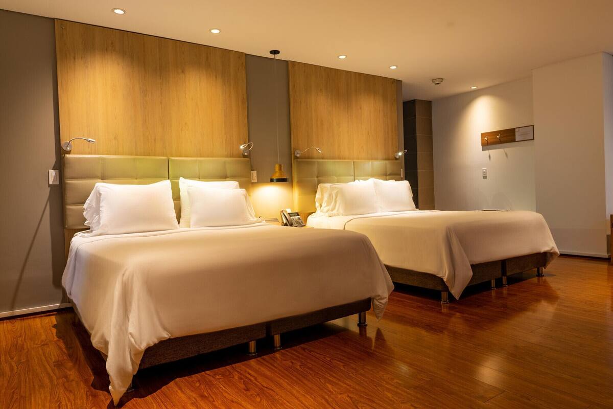 Une chambre d’hôtel avec deux lits, des têtes de lit en bois et un plancher en bois.