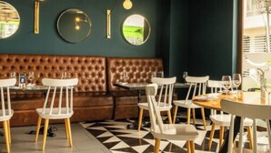 A restaurant interior with a dark green wall, a brown leather booth, and a black and white patterned floor. - Hotel Quo Quality Manizales (Manizales)