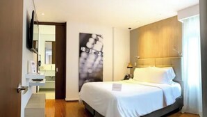 A hotel room with a bed, a flat-screen TV mounted on the wall, a wooden headboard, and a large abstract painting. - Hotel Quo Quality Manizales (Manizales)